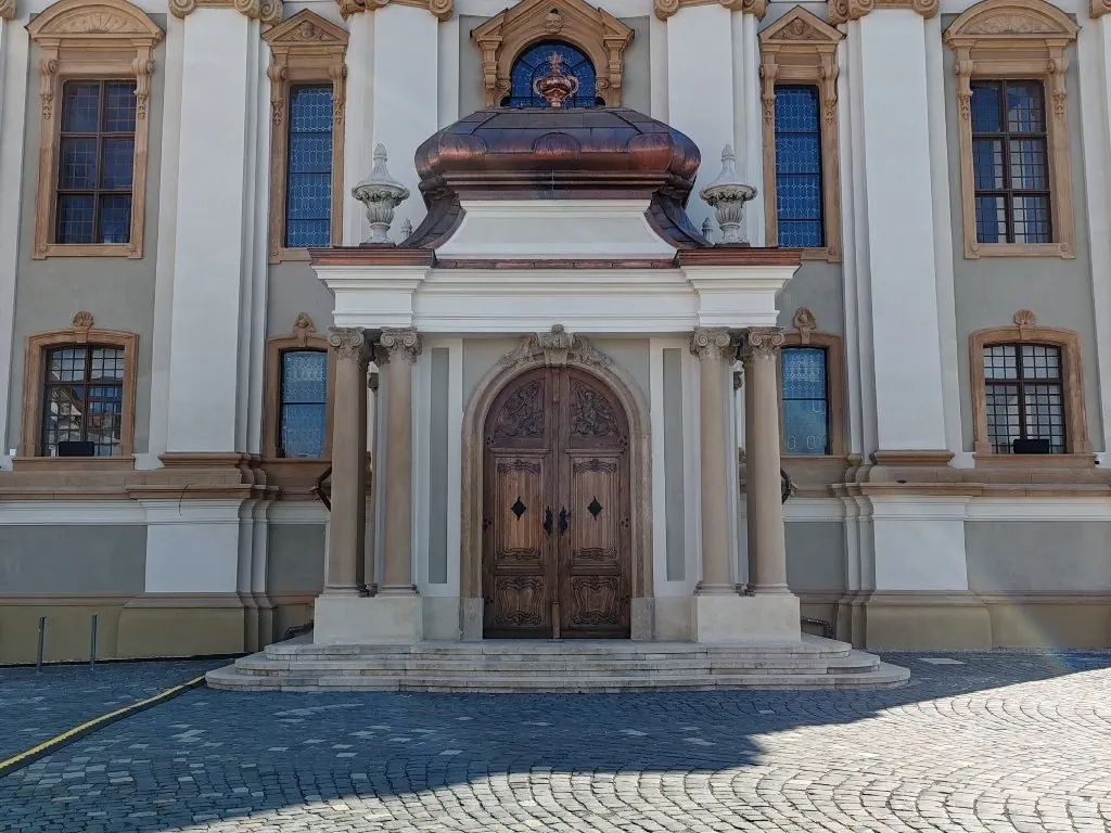 Intrarea principală a Bisericii Romano-Catolice din Piața Unirii Timișoara, cu ușă sculptată din lemn.
